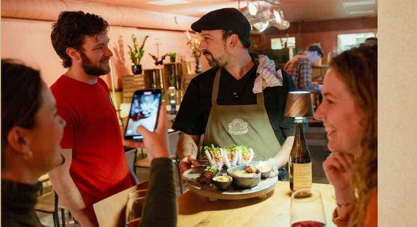 Gasten aan de bar van De Tafelaar, de keuken op de achtergrond